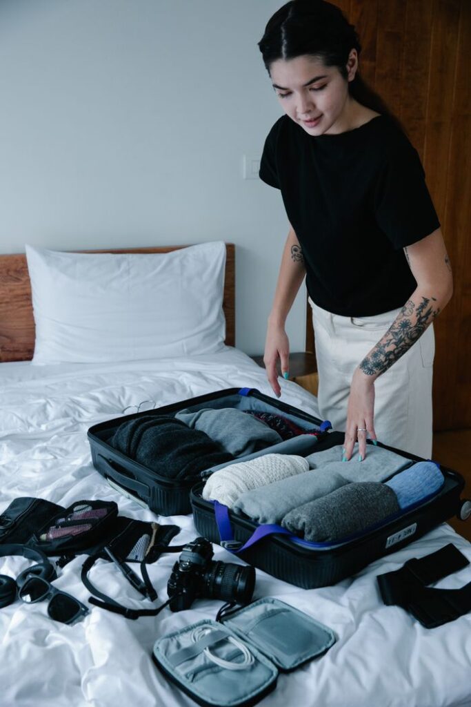 Woman packing neatly organized suitcase on bed for travel preparation.